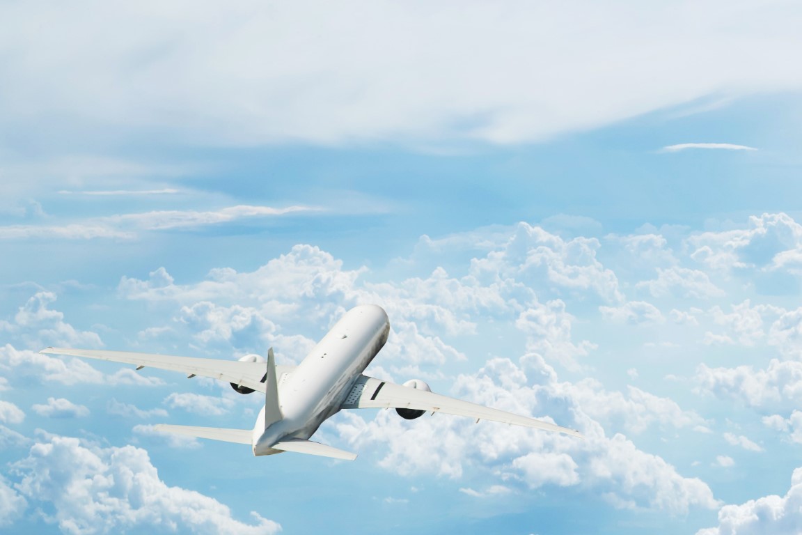 Back view of commercial airplane flying above clouds. Copyspace for text