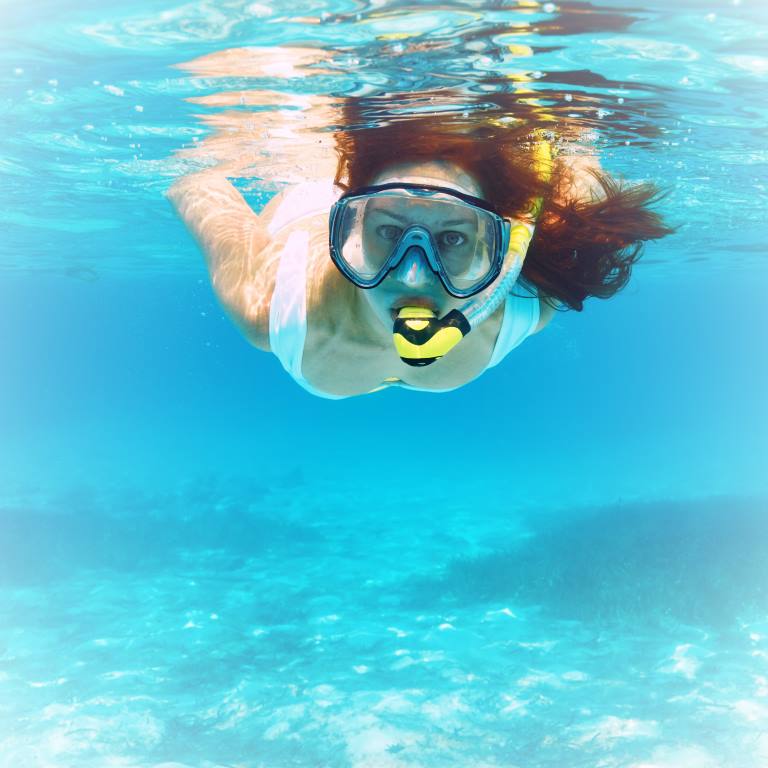 Woman with mask snorkeling in clear water